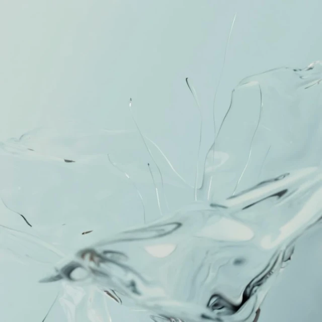 Abstract close-up of transparent liquid in motion, creating a dynamic splash against a pale background, artistic and clean look.