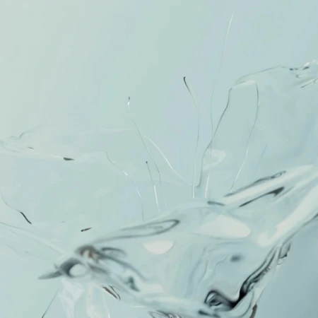 Abstract close-up of transparent liquid in motion, creating a dynamic splash against a pale background, artistic and clean look.