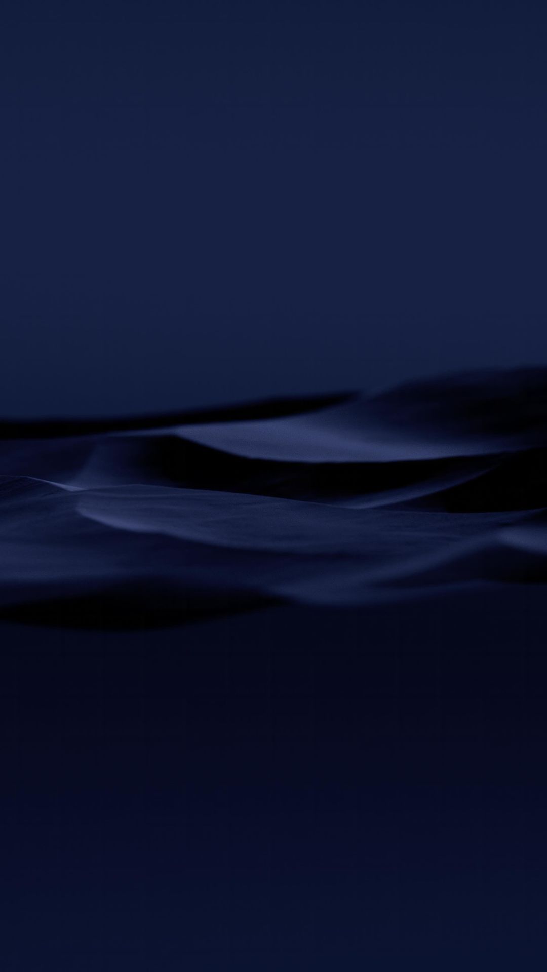 Abstract photograph of rolling, dark blue-toned dunes in a minimalist composition, evoking mystery and tranquility.