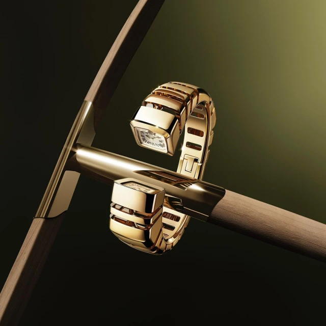 Elegant gold Bulgari Serpenti Seduttori watch featuring a snake-like flexible bracelet design, presented on a gold metal stand against a dark background.