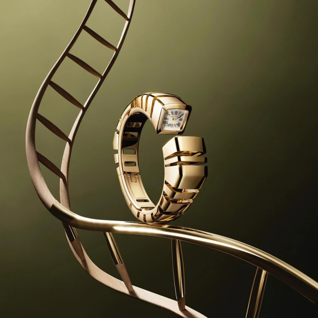 Elegant gold Bulgari Serpenti watch displayed on a stylized gold metal framework against a dark olive green background in studio lighting.