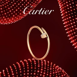 Cartier gold nail bracelet with diamond accents centered against a dark red backdrop with red light patterns