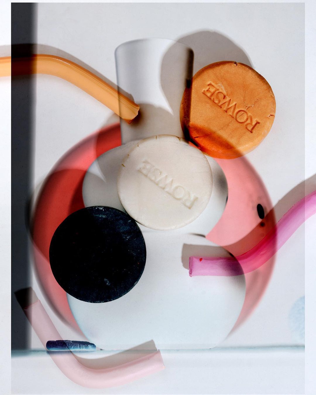 Still life composition of white and red ceramic vase with colorful geometric shapes and beauty product discs, studio shot.