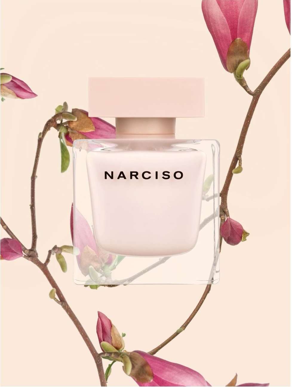 A bottle of Narciso Rodriguez perfume is set against a soft floral background, featuring blossoms and delicate branches in a beauty still life.