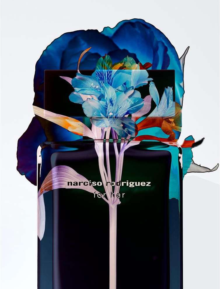 Artistic product shot of a black perfume bottle with blue and white floral accents, and the words 'NARCISO RODRIGUEZ for her' printed on it.