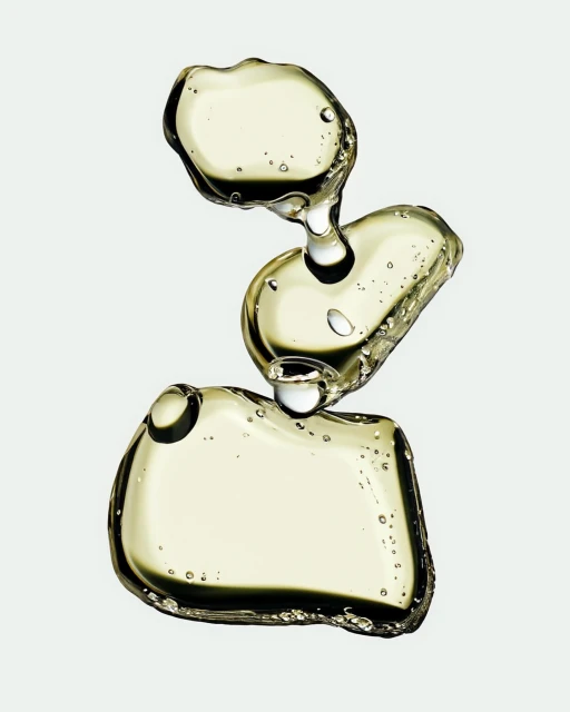 Stacked transparent oil globules catch light against a neutral background, showcasing texture and form in a macro still life.