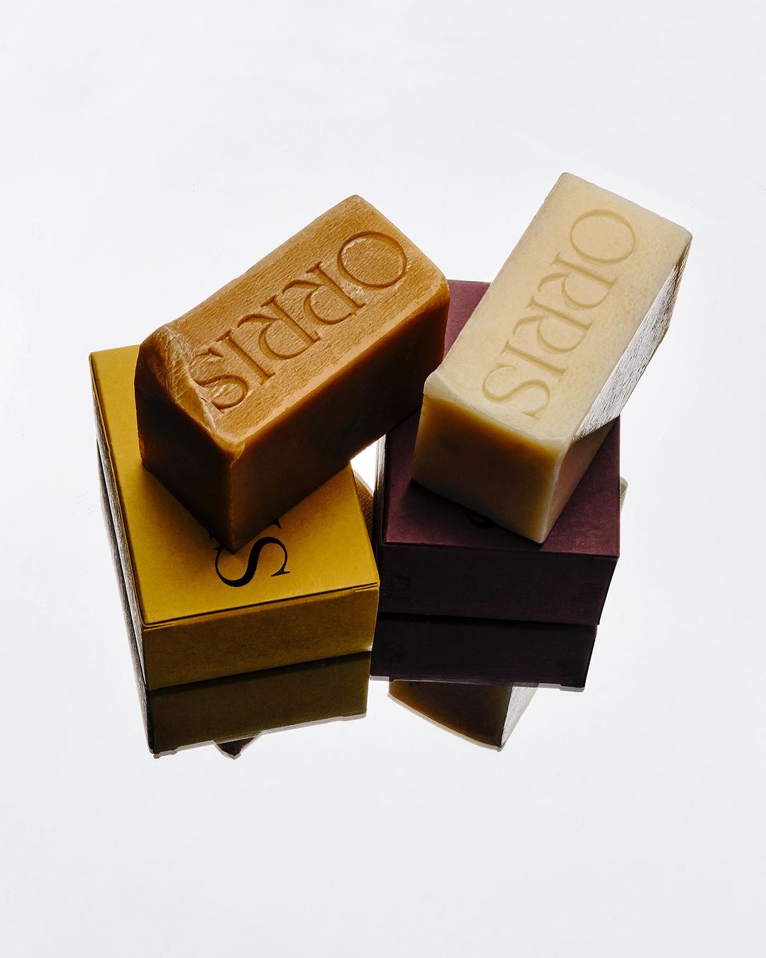 Artisan soaps stacked on boxes feature brand name ORRIS. The image is well-lit, highlighting textures and packaging details.