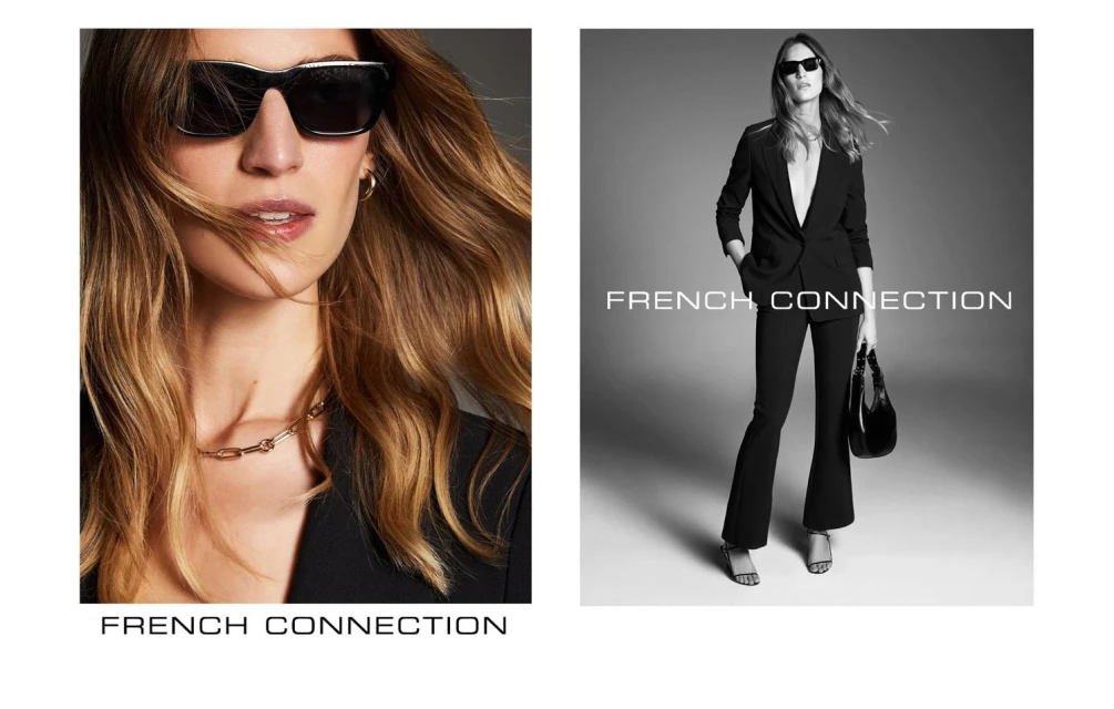 A black and white fashion ad featuring two stylish adult women wearing blazers, sunglasses, and fashionable jewelry, set indoors.
