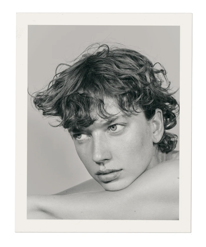 Close up monochrome portrait of a person with curly hair resting chin on arm, by Manolo Campion