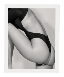 Close-up profile of a woman wearing a black high-cut swimsuit against a neutral backdrop framed by a polaroid border.