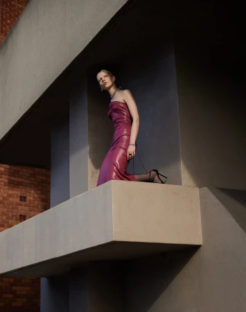 Model in strapless magenta dress posing on a concrete architectural balcony by Manolo Campion