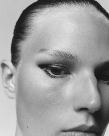 Close-up portrait of a woman with slicked-back dark hair and dramatic winged eyeliner by Benjamin Vnuk