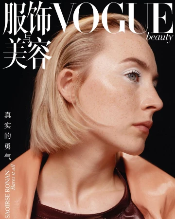 Portrait of Saoirse Ronan with freckles and slicked-back blonde hair against a black background shot by Benjamin Vnuk.