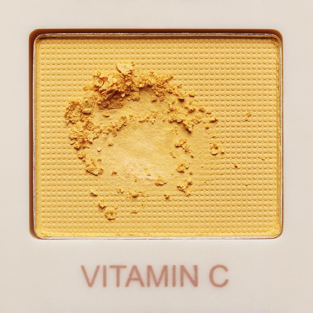 Close-up of yellow Vitamin C powder in a white cosmetic palette. Beauty and skincare product.