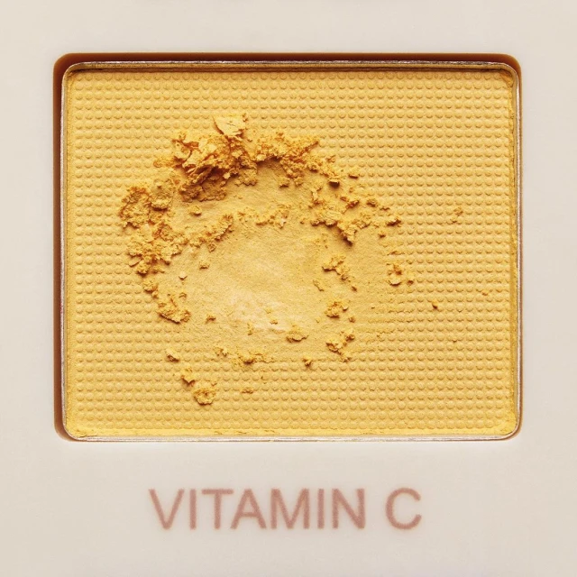 Close-up of yellow Vitamin C powder in a white cosmetic palette. Beauty and skincare product.