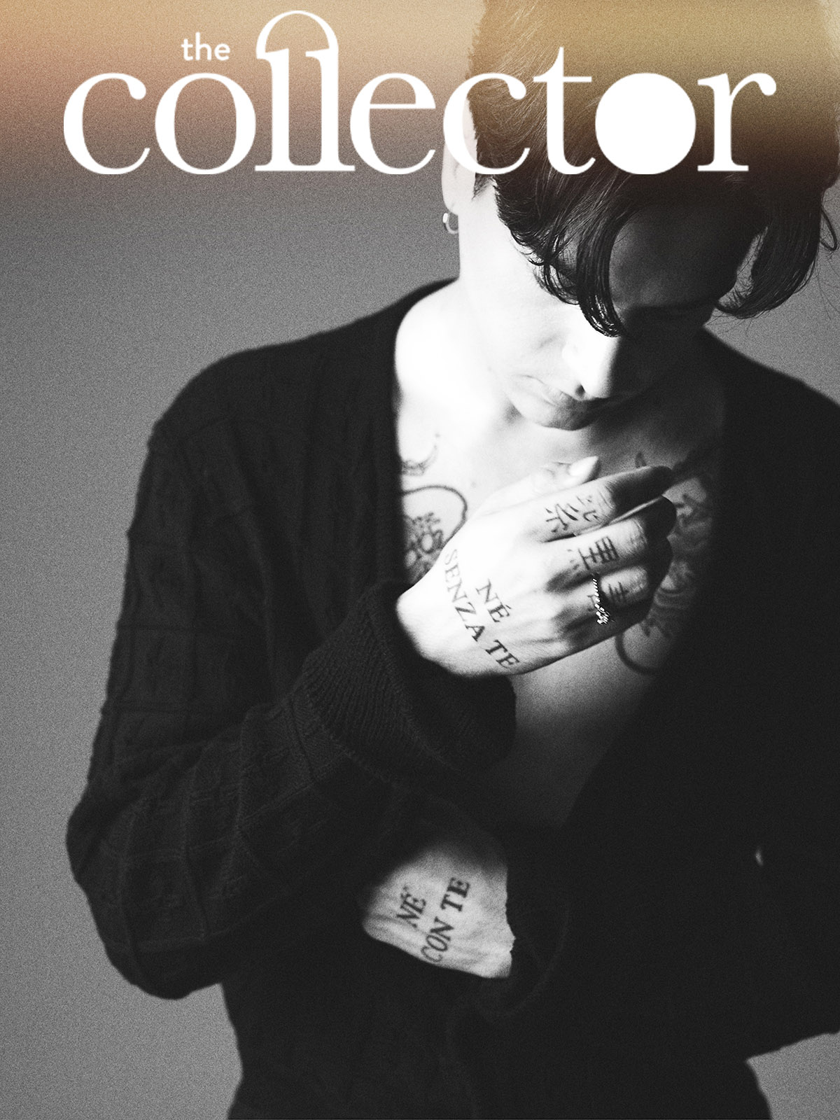 Magazine cover featuring a person with tattoos, wearing a black cardigan, set against a neutral background, displaying monochrome artistic styling.
