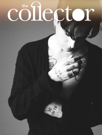 Magazine cover featuring a person with tattoos, wearing a black cardigan, set against a neutral background, displaying monochrome artistic styling.