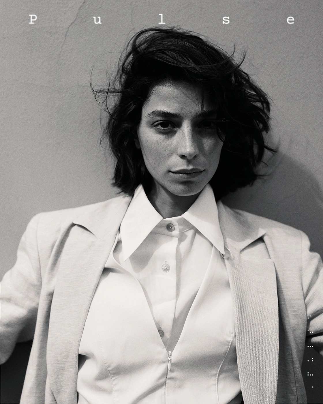 Monochrome portrait of a woman with dark wavy hair wearing a tailored white shirt and blazer by photographer Simone Paccini.