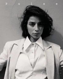 Monochrome portrait of a woman with dark wavy hair wearing a tailored white shirt and blazer by photographer Simone Paccini.