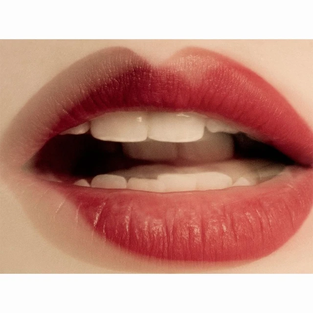 Macro view of human mouth with red lipstick and white teeth. A close-up on a person's lips, teeth, and surrounding skin detail.