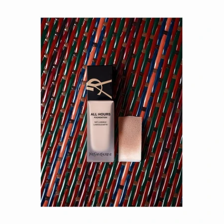 Yves Saint Laurent All Hours Foundation bottle with applicator, product shot on a textured multicolored surface, makeup and beauty.