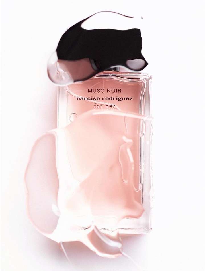 Product shot of a Narciso Rodriguez 'Musc Noir for her' perfume bottle with black cap and light pink liquid against a white background.