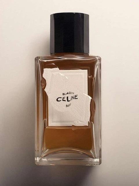 Still-life studio shot of a CELINE Black Tie fragrance bottle with a black cap and a beige label on a neutral background.