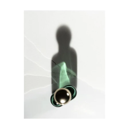 A modern still life photograph with a glass bottle casting a dark shadow on a plain white background with subtle light leaks and textures.