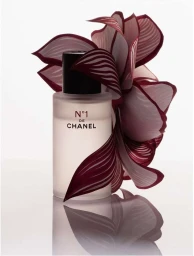 Chanel fragrance bottle with translucent frosted glass and a large red petal-like paper sculpture behind it on white seamless background