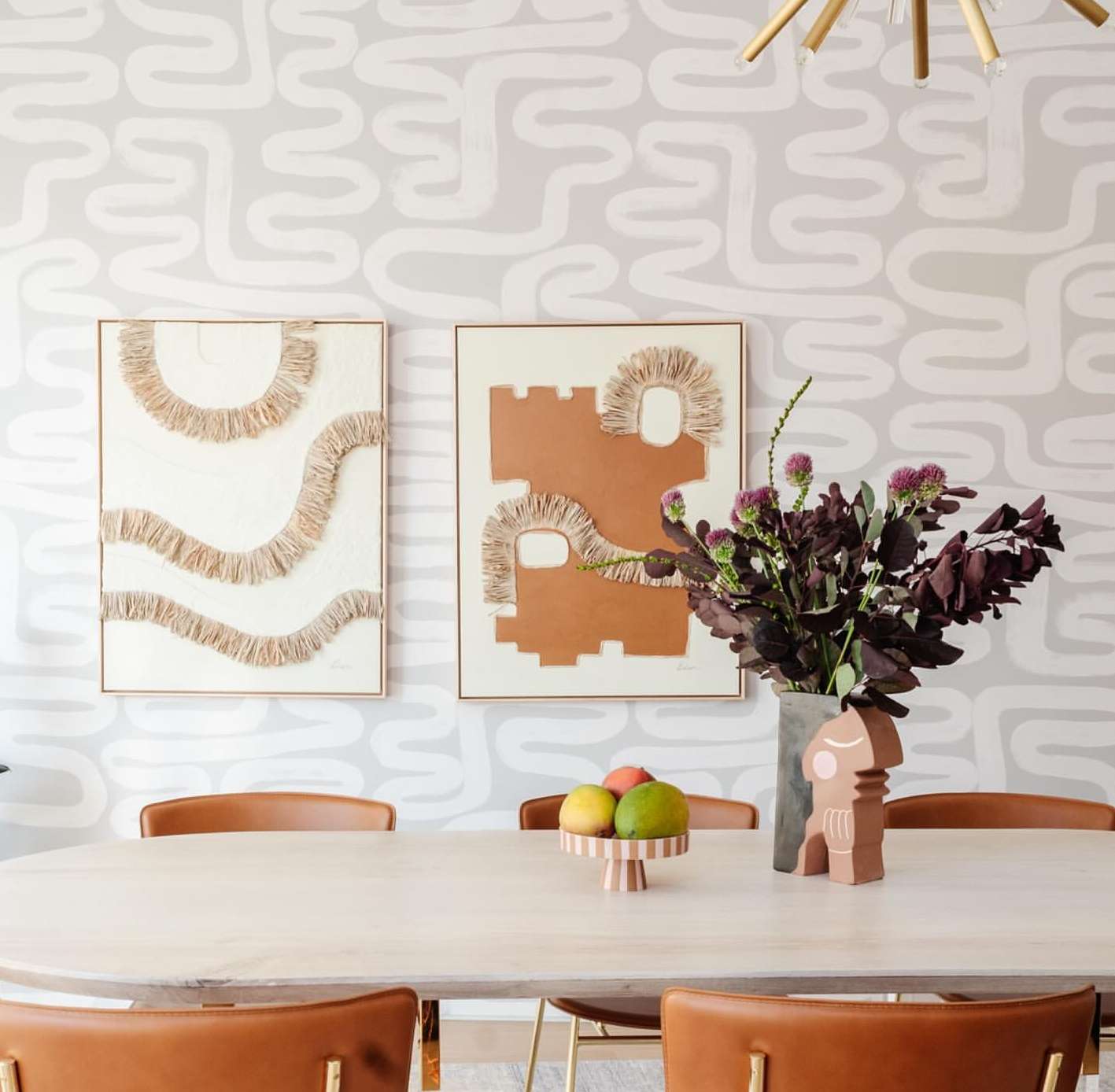 Home interior features abstract artwork on walls, oval dining table with fruit, stylish chairs, and decorative ceramic object.