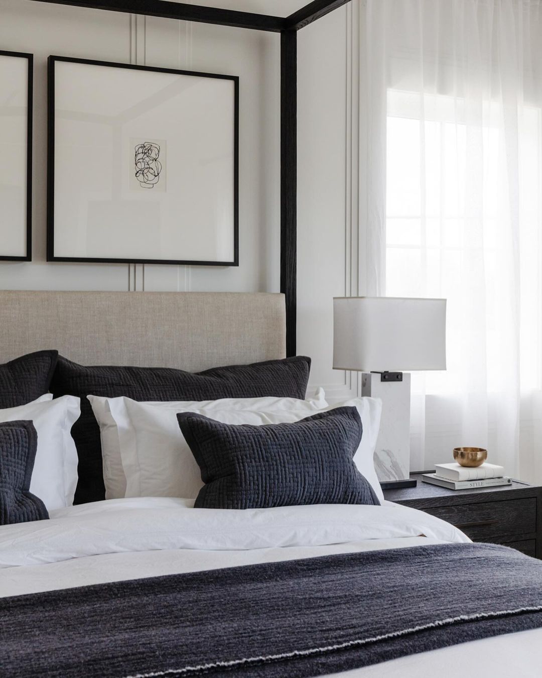 Bedroom interior featuring a bed with gray pillows, white sheets, a gray throw, and a black-framed art print above the headboard.