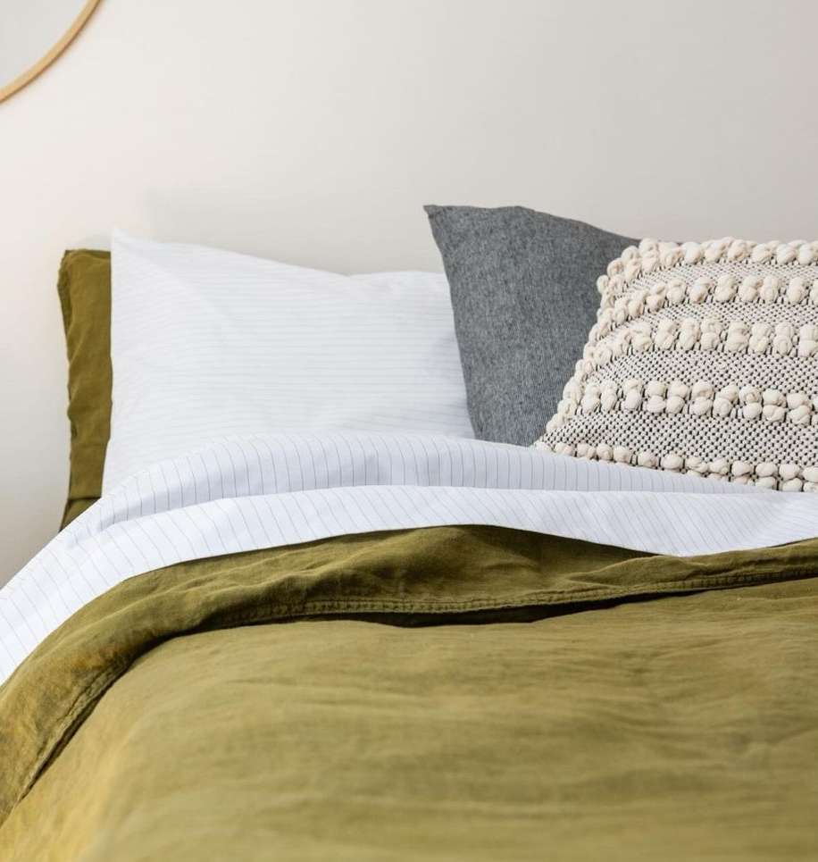 Olive green duvet cover and decorative pillows in an interior setting, showcasing a cozy and inviting bedroom arrangement.