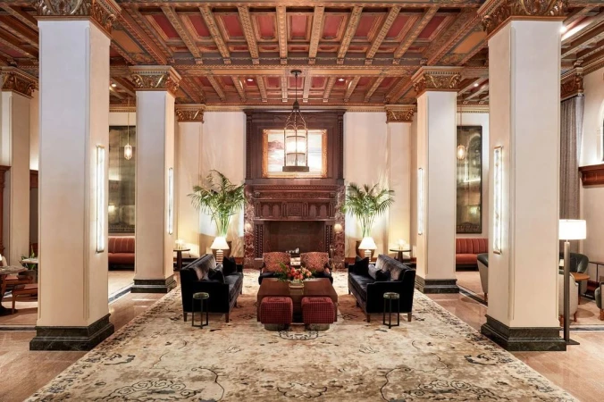 Grand hotel lobby interior with ornate coffered ceiling, large columns, fireplace, and velvet sofas photographed by Bethany Nauert