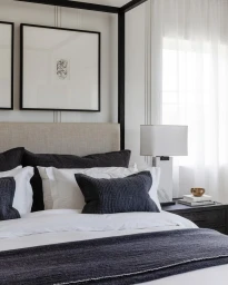 Modern canopy bed featuring dark charcoal pillows and white linens with framed artwork above, photographed by Bethany Nauert