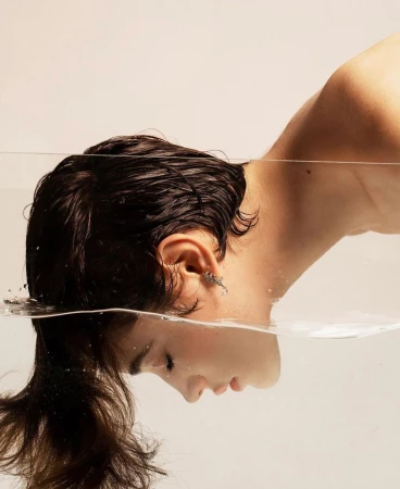 Close-up profile portrait of a woman with wet dark hair half-submerged in water by photographer Betina Du Toit
