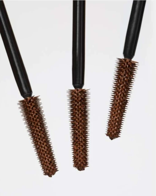 Close-up studio shot of three brown mascara wands with black handles against a white background, perfect for beauty and makeup.