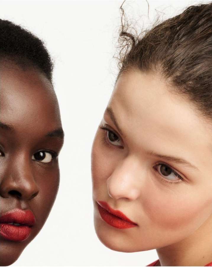 Close-up portrait of two female models with red lipstick against a plain white background by Betina Du Toit
