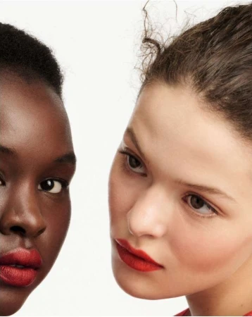 Close-up portrait of two female models with red lipstick against a plain white background by Betina Du Toit