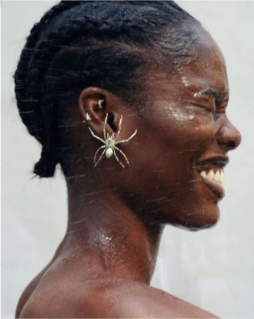 Profile shot of an African American adult female with braids, eyes closed, and a silver spider earring with white background.