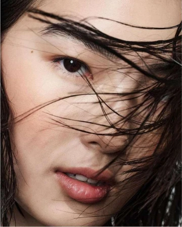 Close-up beauty portrait of a woman with wet dark hair strands falling across her face shot by Betina Du Toit