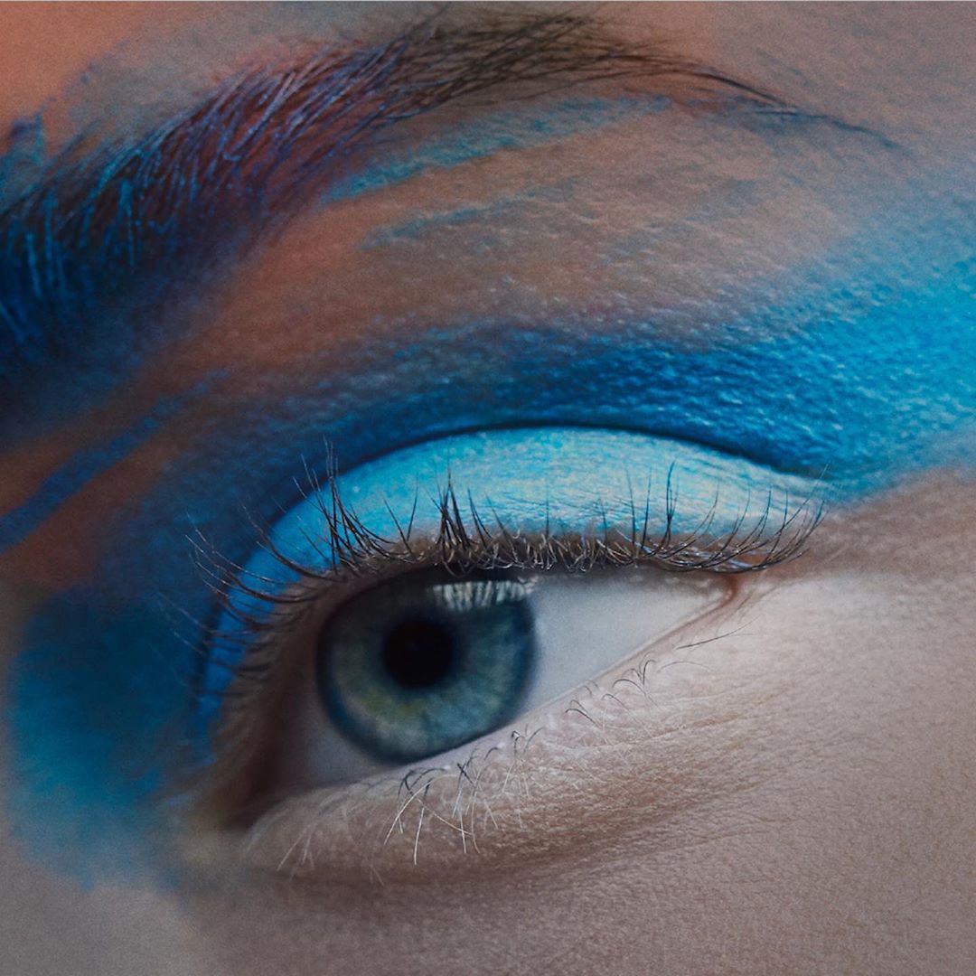 Close-up of a blue eye with vibrant blue makeup, highlighting the eye's natural color and enhancing its appearance with cosmetic artistry.