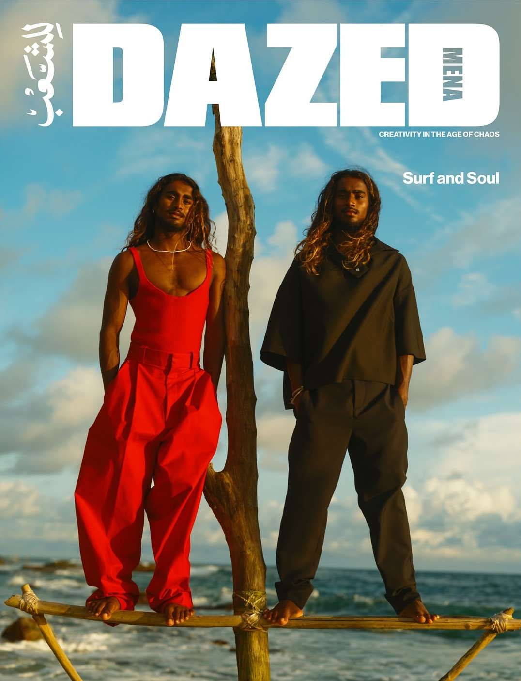 Two men in stylish outfits pose on a wooden structure by the ocean. Magazine cover with 'Dazed' logo against a partly cloudy sky.