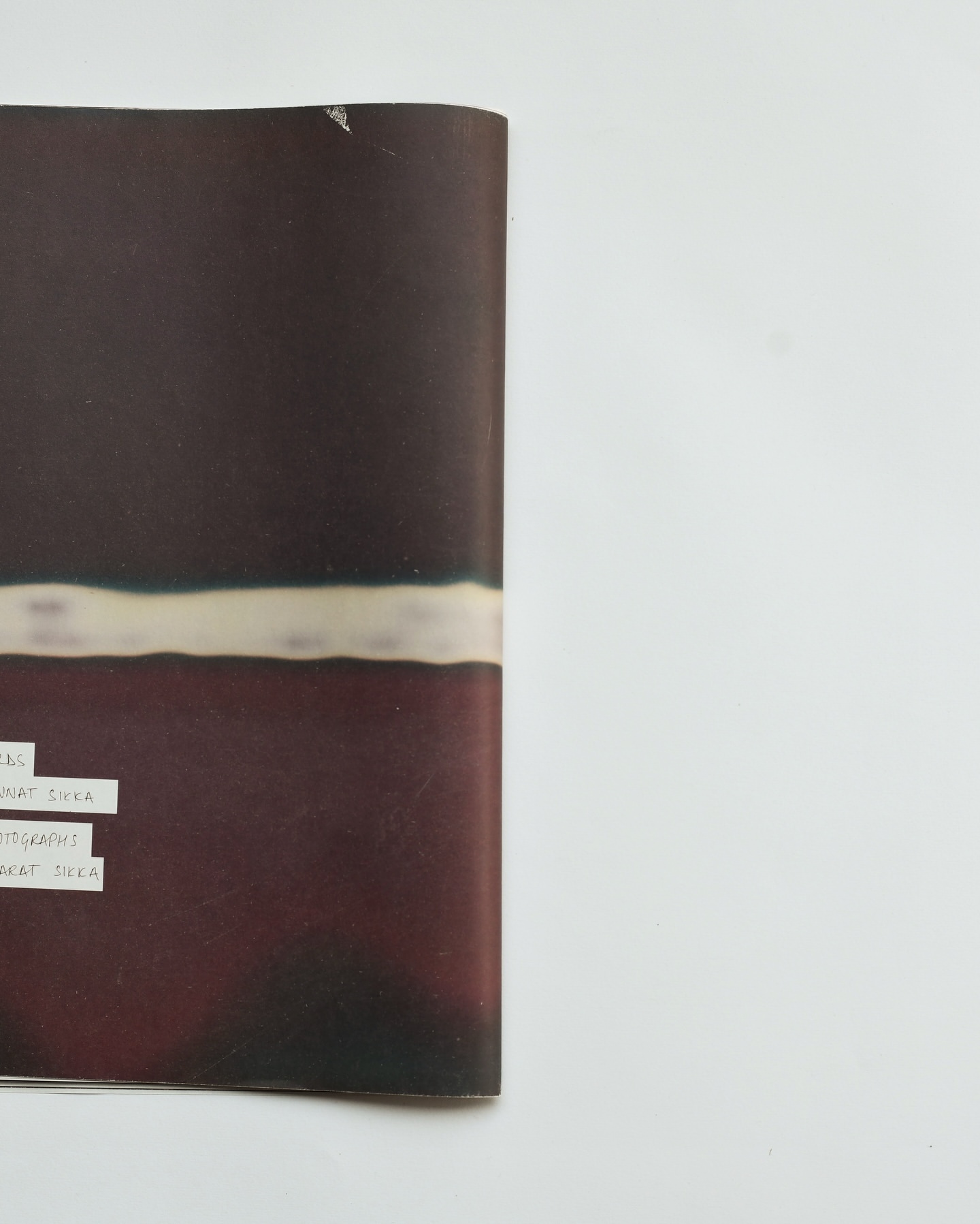 Abstract image of an open magazine page displaying blurred horizontal lines in shades of brown, cream, and black against a white backdrop.