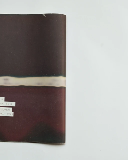 Abstract image of an open magazine page displaying blurred horizontal lines in shades of brown, cream, and black against a white backdrop.