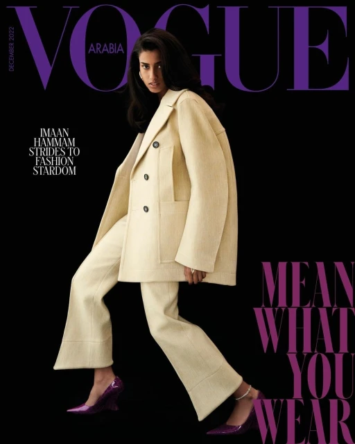 Vogue Arabia cover featuring model Imaan Hammam in a cream pantsuit and purple heels, posing against a black background with magazine text.