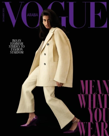 Vogue Arabia cover featuring model Imaan Hammam in a cream pantsuit and purple heels, posing against a black background with magazine text.