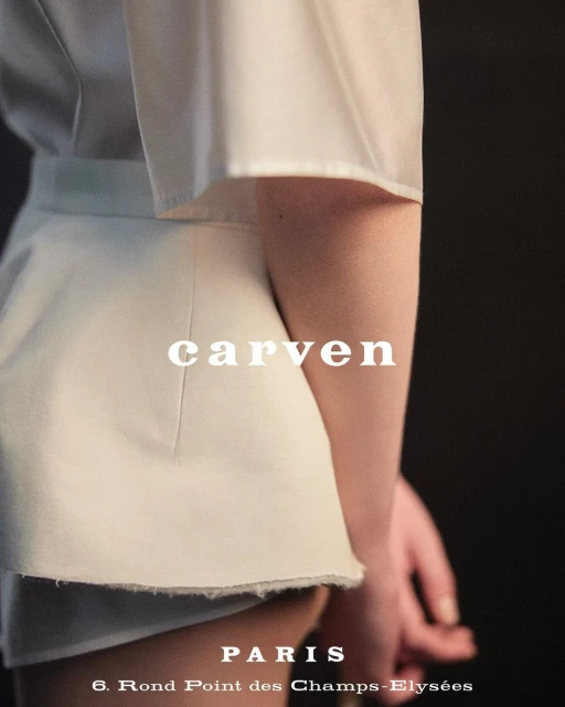 Fashion shot featuring a model wearing a white Carven skirt and top against a dark background, showcasing the brand's design.