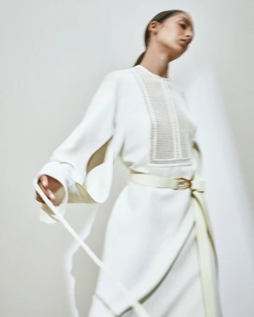 Model in a cream white long-sleeved dress with a belted waist against a neutral backdrop by Bibi Cornejo Borthwick
