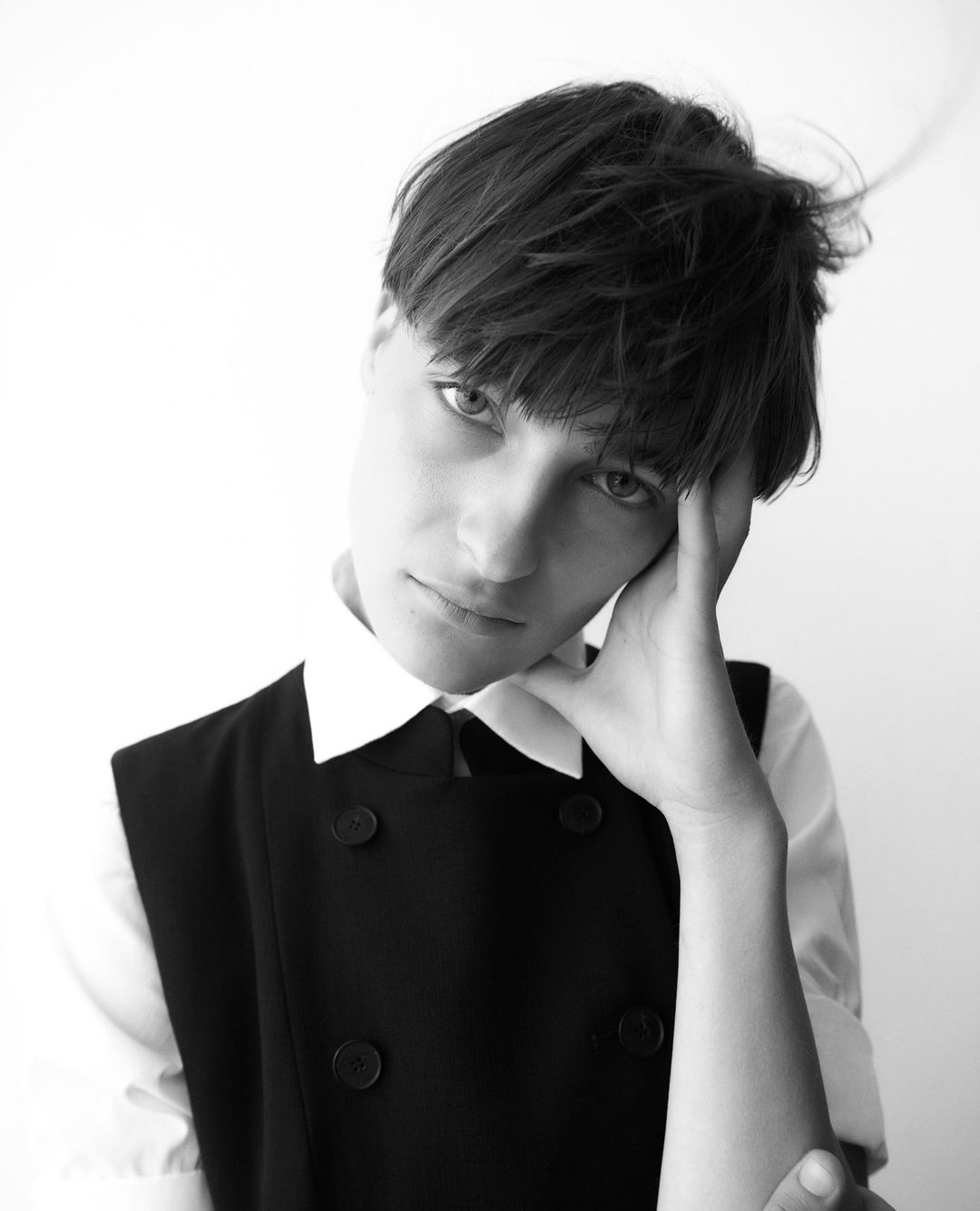 Portrait of a short-haired person in a white collared shirt and black double-breasted vest