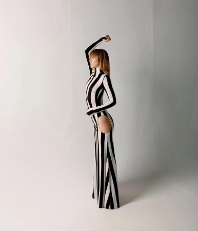 Model in a black and white striped dress with side cutout posing against a white seamless background